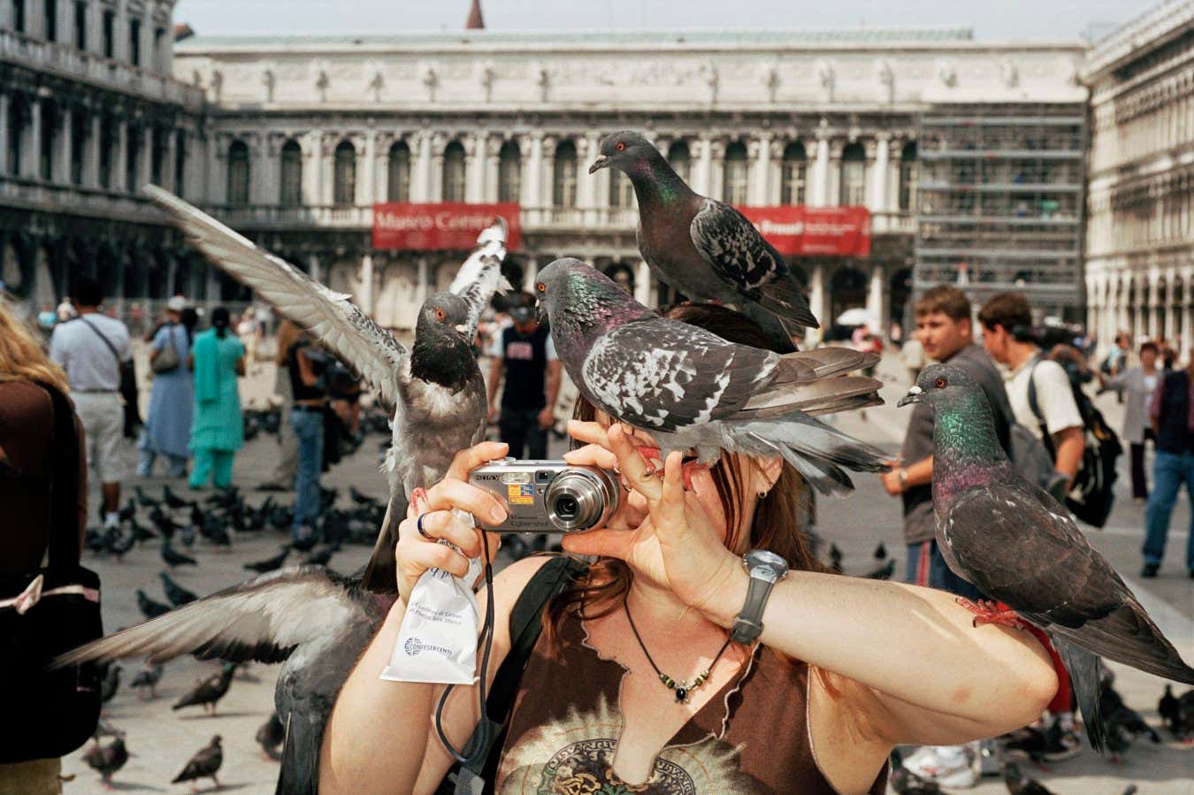 ITALY. Venice. Turystka fotografująca się w otoczeniu gołębi. 2005.